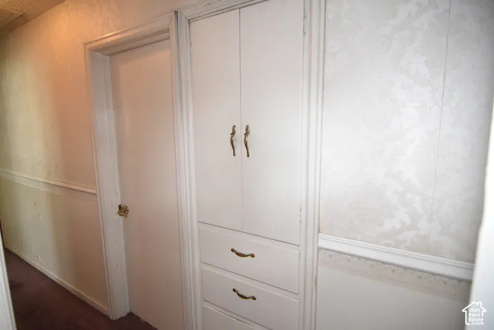Built-in storage cabinet with brass hardware, wood paneling, and patterned wallpaper