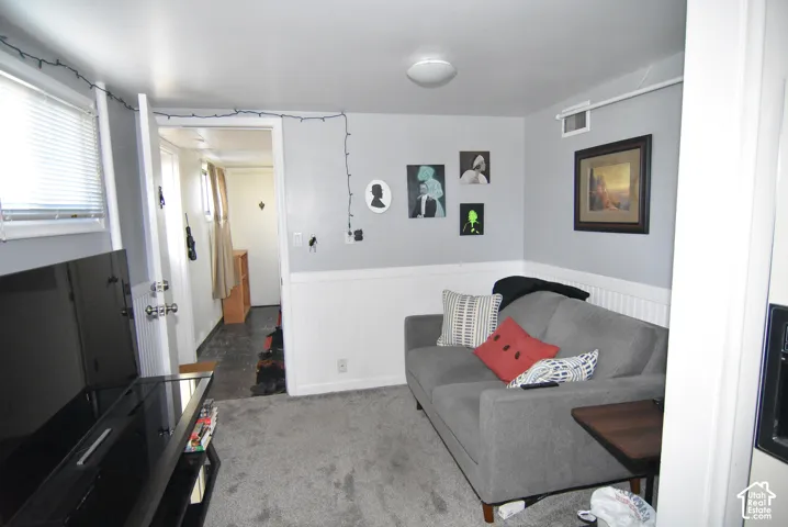 Private basement entry.  Front living room of the ADU Recessed windows with blinds, gray wall paint, white wainscoting, and a ceiling-mounted light fixture