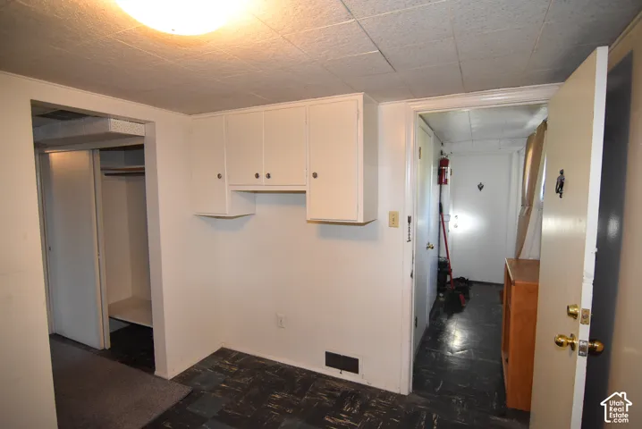 Workshop or hobby room with white cabinetry with shelving, acoustic tile ceiling, and a built-in closet with sliding doors