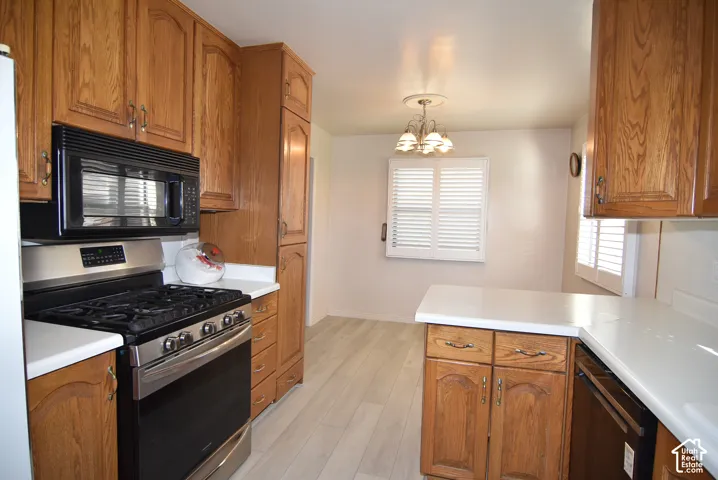 Kitchen featuring wood cabinetry, white countertops, stainless steel gas range, built-in microwave, and wood-finish flooring