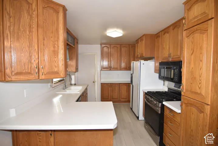 Kitchen featuring wood-finish cabinetry, white countertops, built-in microwave, and a gas range