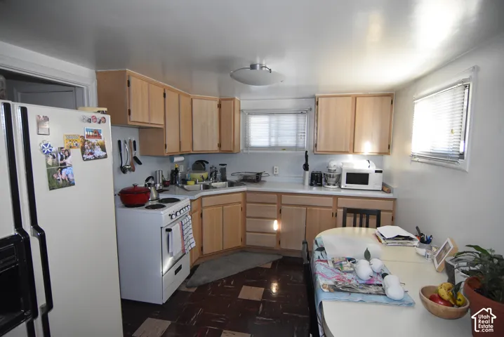 Kitchen featuring light wood-finish cabinetry, white countertops, built-in sink, white range, and white refrigerator