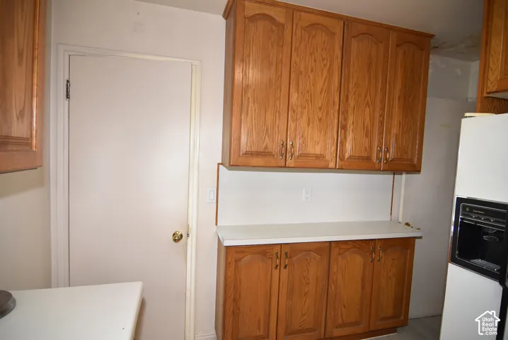 Kitchen featuring wood-finish cabinetry, white countertops, and white appliances