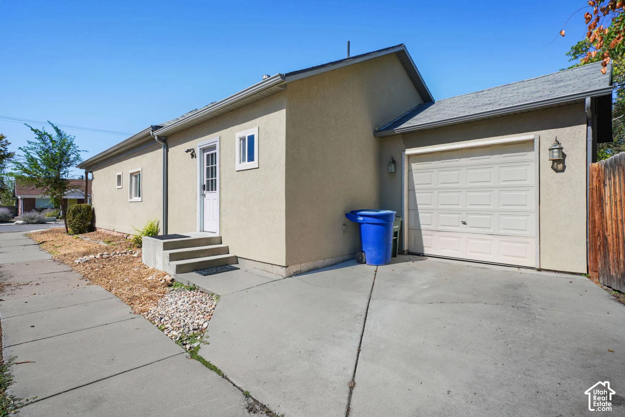 Concrete driveway, attached garage, stucco exterior, side entry door, and concrete walkway