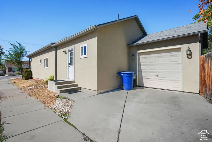 Concrete driveway, attached garage, stucco exterior, side entry door, and concrete walkway