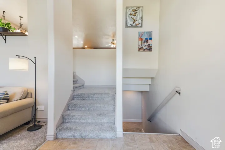 Carpeted stairs leading to an upper level, with a half-wall balcony and a ceiling fan visible