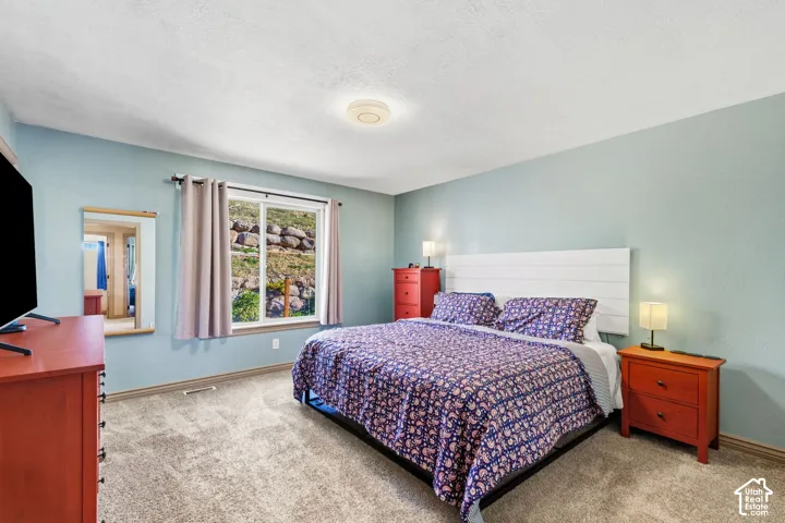 Recessed ceiling light, textured ceiling, a window with outdoor scenery, and light-colored carpeting