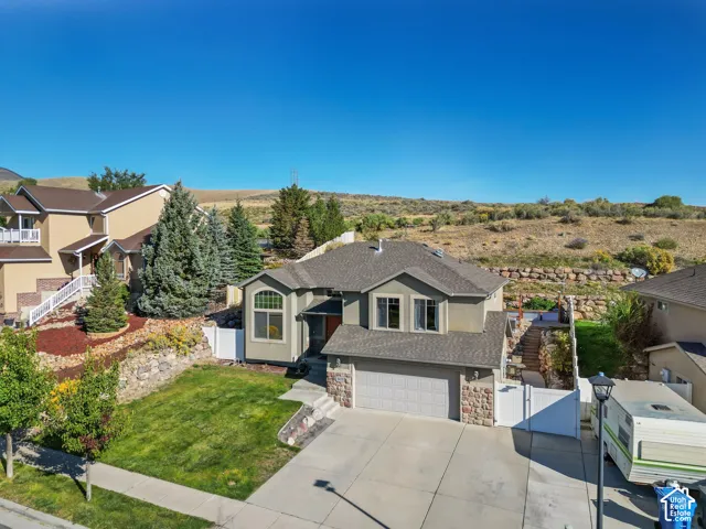 Two-story residence with a two-car garage, stone and stucco exterior, and a concrete driveway