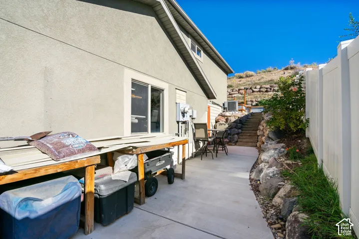 Concrete pathway with a rock retaining wall, leading to exterior stairs