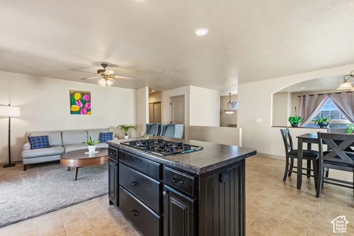 Kitchen island with built-in cooktop, tile flooring, recessed lighting, and an arched pass-through window