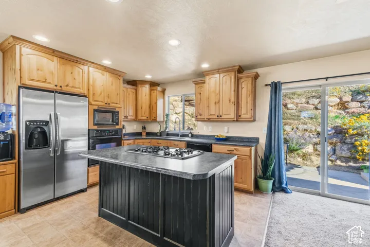 Recessed lighting illuminating the kitchen with wood cabinetry and stainless steel appliances