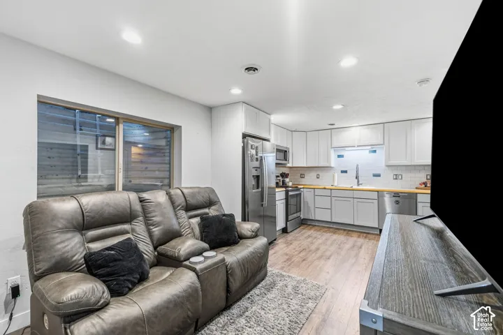 Kitchen featuring white shaker cabinetry, wood-finish countertops, stainless steel appliances, and a tile backsplash