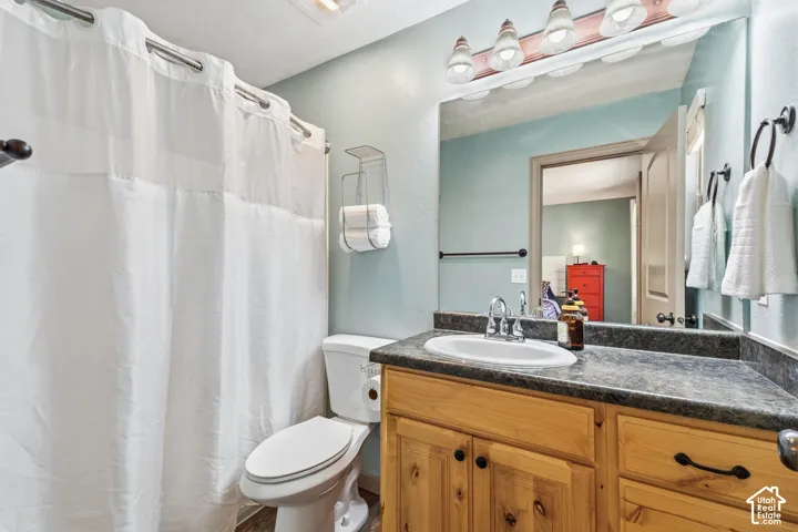 Bathroom featuring a single vanity with wood-finish cabinetry, a white basin sink, and a dark countertop