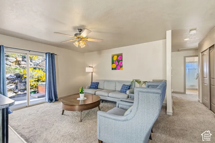 Sliding glass door, light-colored carpet, ceiling fan with integrated lighting, built-in closet with double doors, and recessed lighting in the hallway