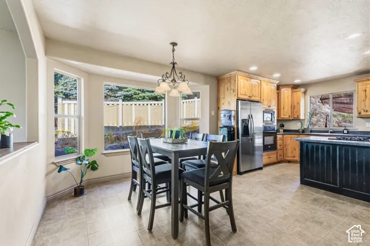 Bay window, wood cabinetry, stainless steel appliances, dark-toned kitchen island, and tiled flooring