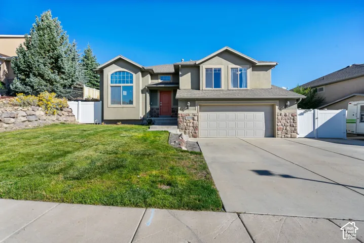 Stucco exterior with stone accents, arched window, attached garage, and a concrete driveway