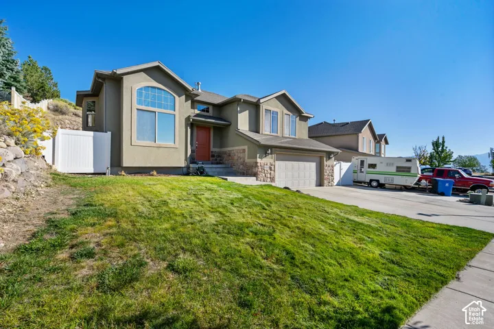 Two-story stucco and stone-clad exterior with an attached garage, arched window, and red entry door