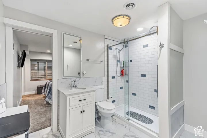Modern bathroom featuring a glass-enclosed shower with subway tile, white vanity with integrated sink, rectangular wall mirror, and marble-finish flooring