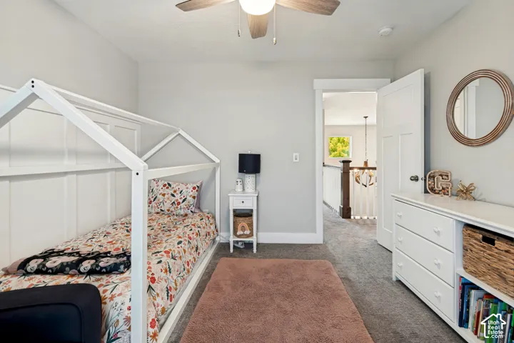 Light gray painted walls, wood-finish ceiling fan, white paneled door, and gray carpeted flooring