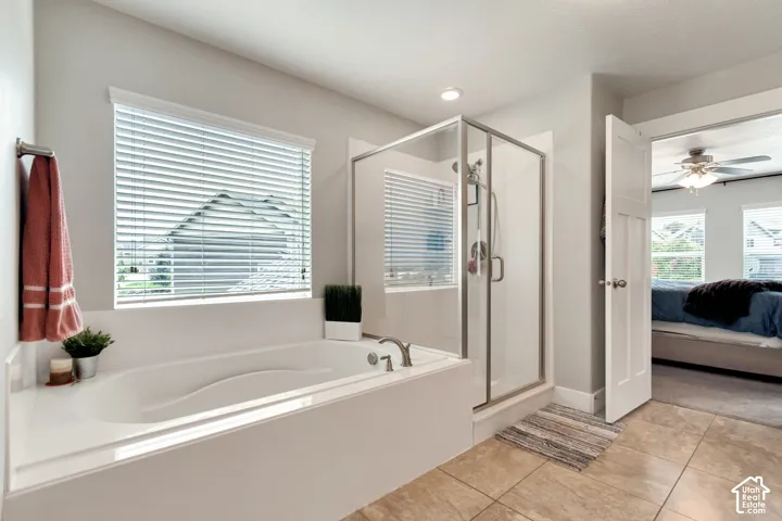 Built-in soaking tub with deck-mounted faucet, glass-enclosed shower, and tile flooring