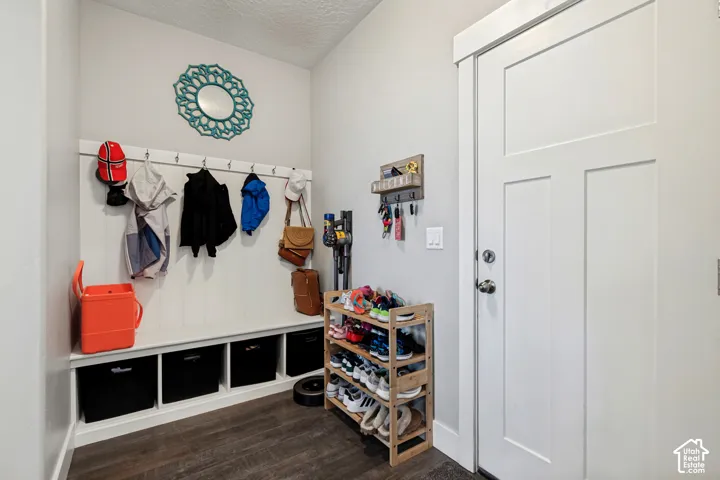 Entryway featuring wood-finish flooring, a built-in bench with integrated storage, and a white paneled door