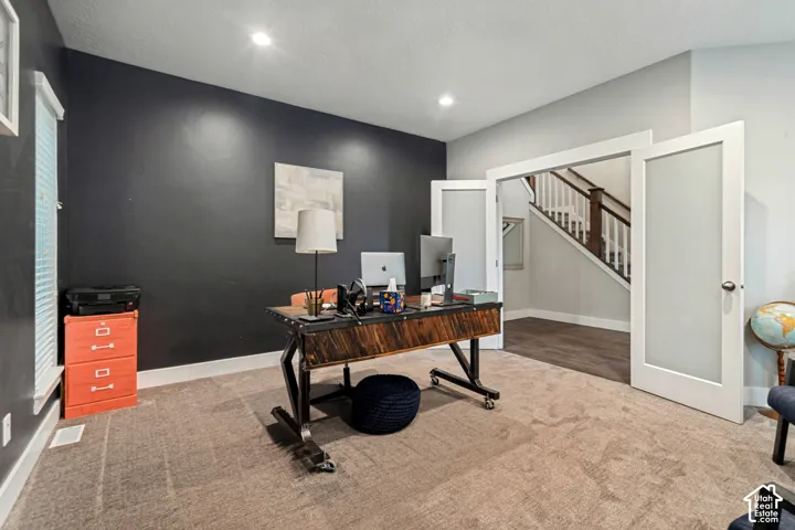 Recessed lighting, dark accent wall, frosted glass French doors, and carpet flooring