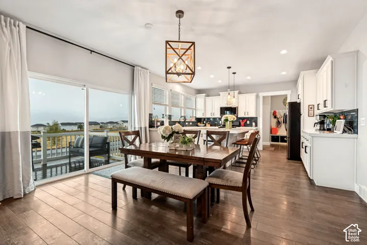 Open-concept dining and kitchen space featuring wood-finish flooring, white cabinetry, recessed lighting, and a sliding glass door leading to a deck