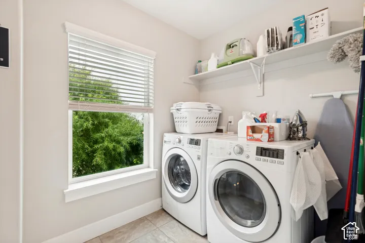 Laundry area featuring tile flooring, a window with horizontal blinds, and a built-in wall shelf