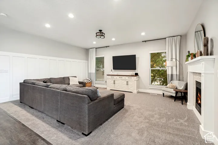 Recessed lighting, board and batten wall detailing, carpeted flooring, built-in fireplace, and expansive windows