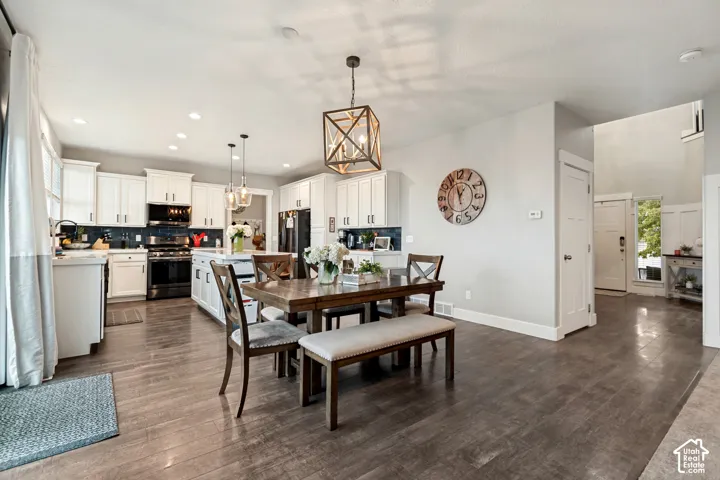 White shaker cabinetry, wood-finish flooring, recessed lighting, island with pendant lighting, and a decorative chandelier