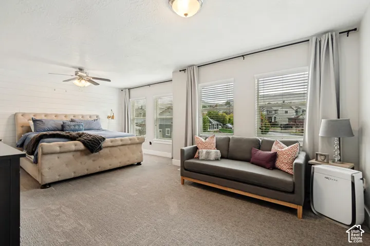Shutter-style window blinds, wall-mounted light fixture, recessed ceiling light, ceiling fan, and carpeted flooring