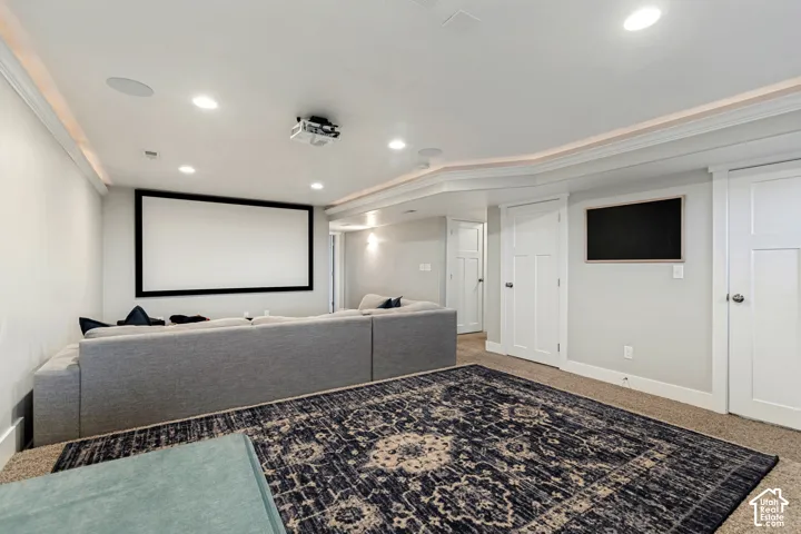 Dedicated media room featuring a large projection screen, recessed lighting, ceiling-mounted projector, and integrated ceiling speakers