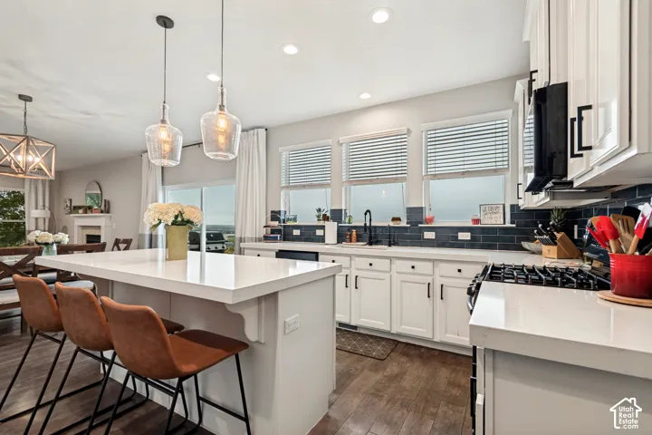 Kitchen featuring white cabinetry, a large center island with a white countertop, dark wood-finish flooring, and a dark blue subway tile backsplash