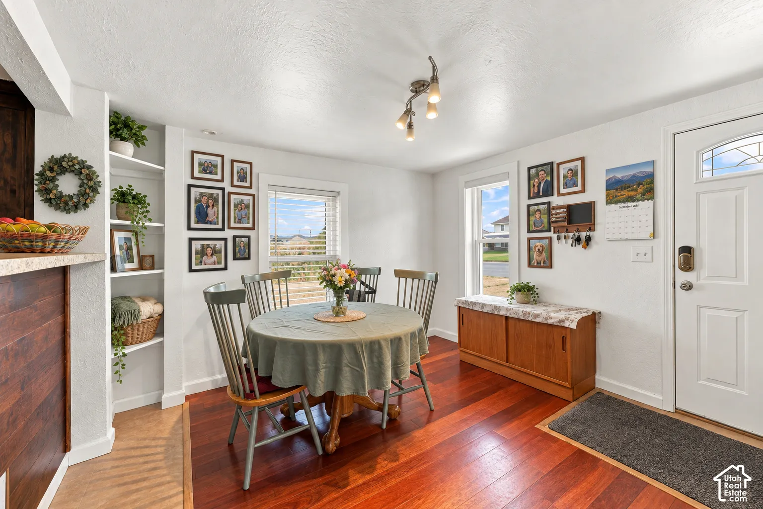 Hardwood flooring, built-in shelving, white trim, and a white entry door with an arched glass insert