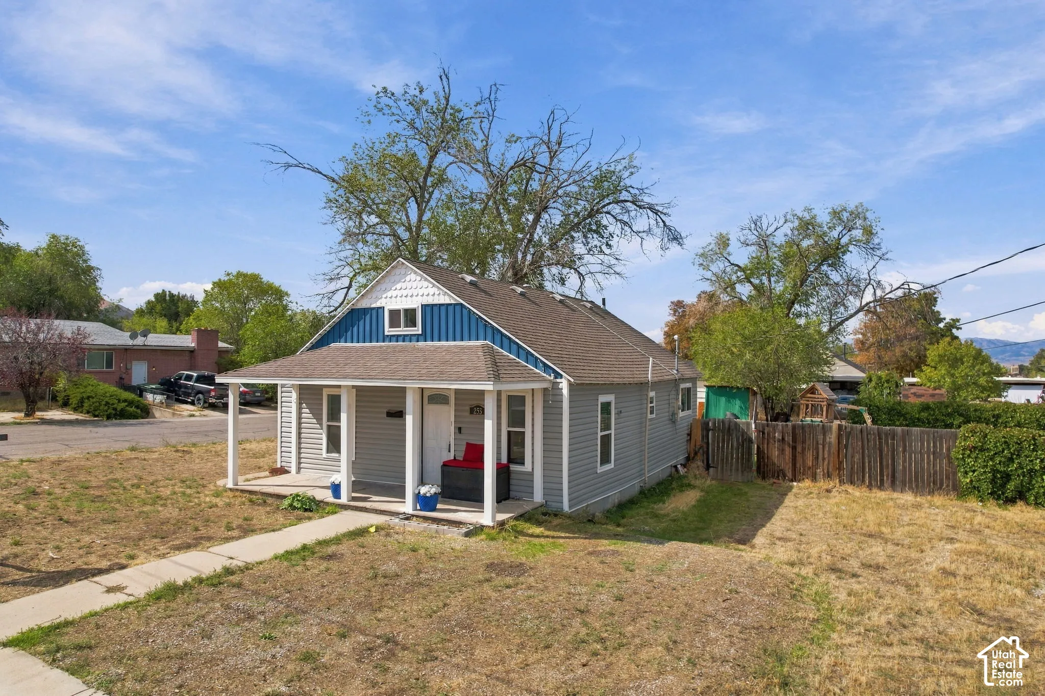 Exterior featuring gray siding, a covered front porch, and a contrasting blue and white gabled facade
