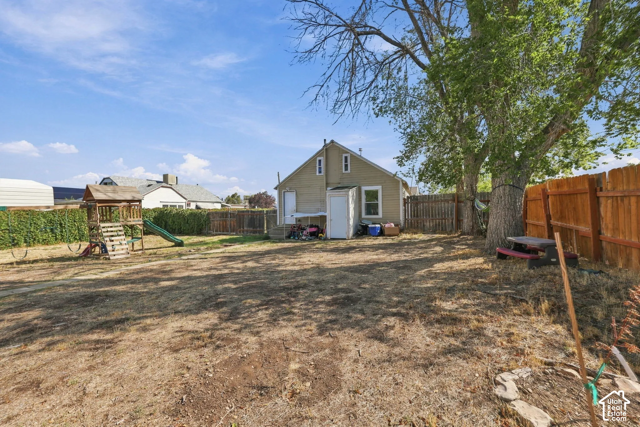 Expansive backyard featuring a wood fence, mature shade trees, and a detached storage shed