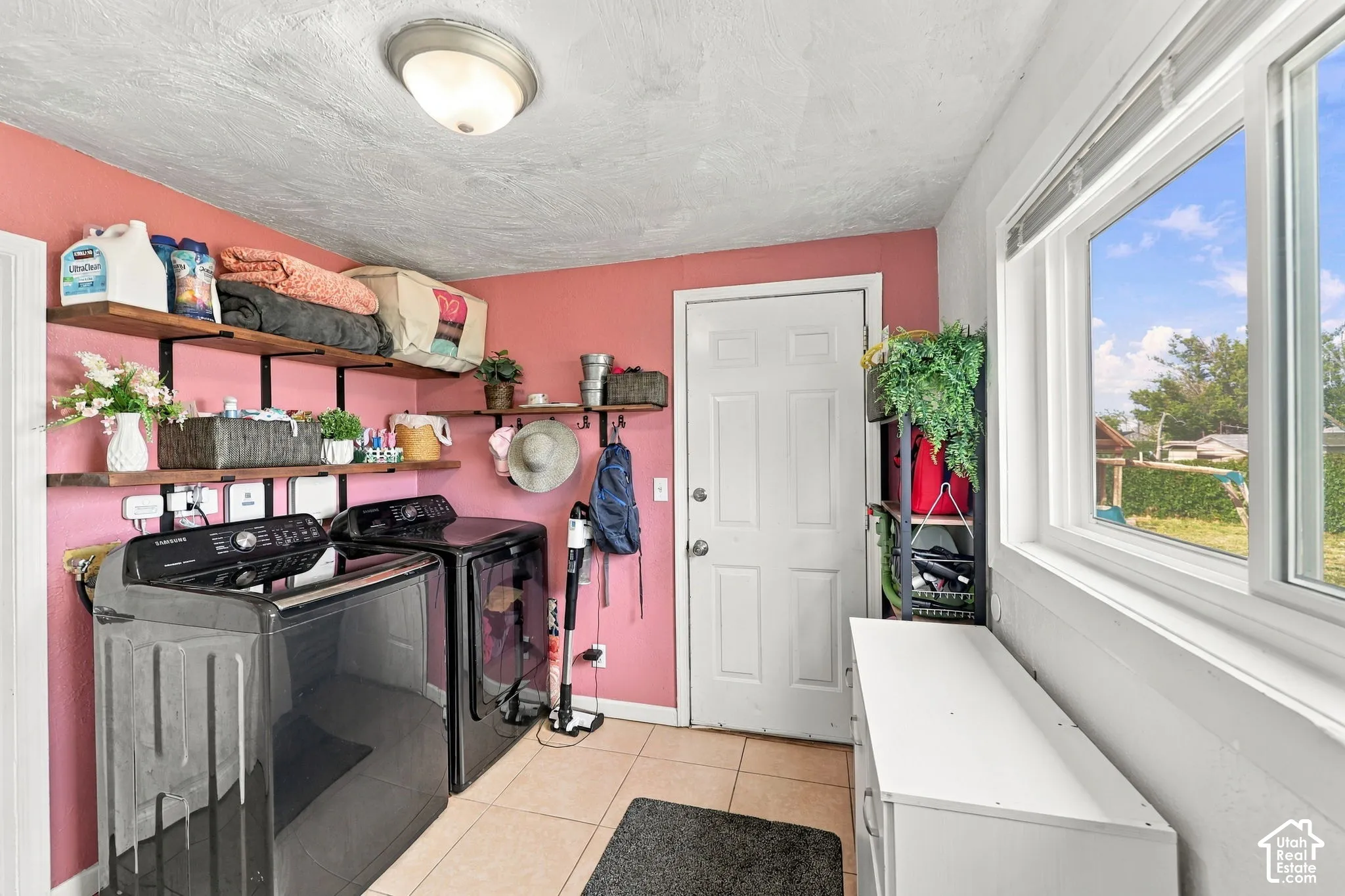 Laundry area featuring neutral tile flooring, a window, and built-in shelving