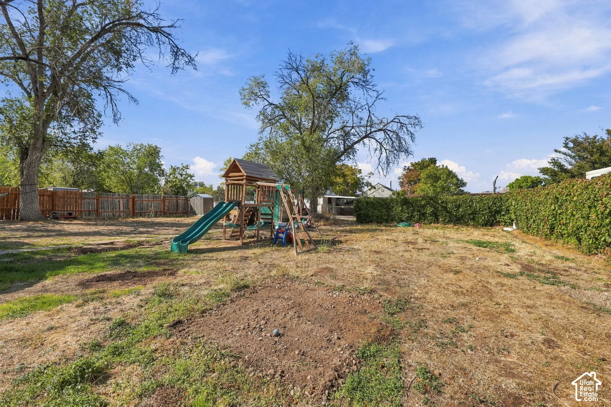 Expansive backyard featuring mature trees, a privacy fence, and a wooden play structure