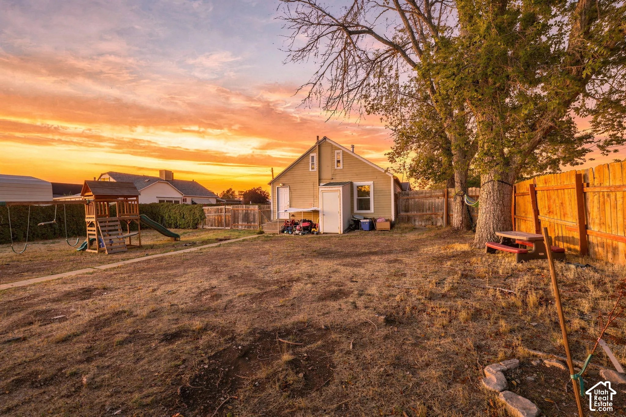 Expansive backyard with a wood privacy fence, mature trees, and a storage shed