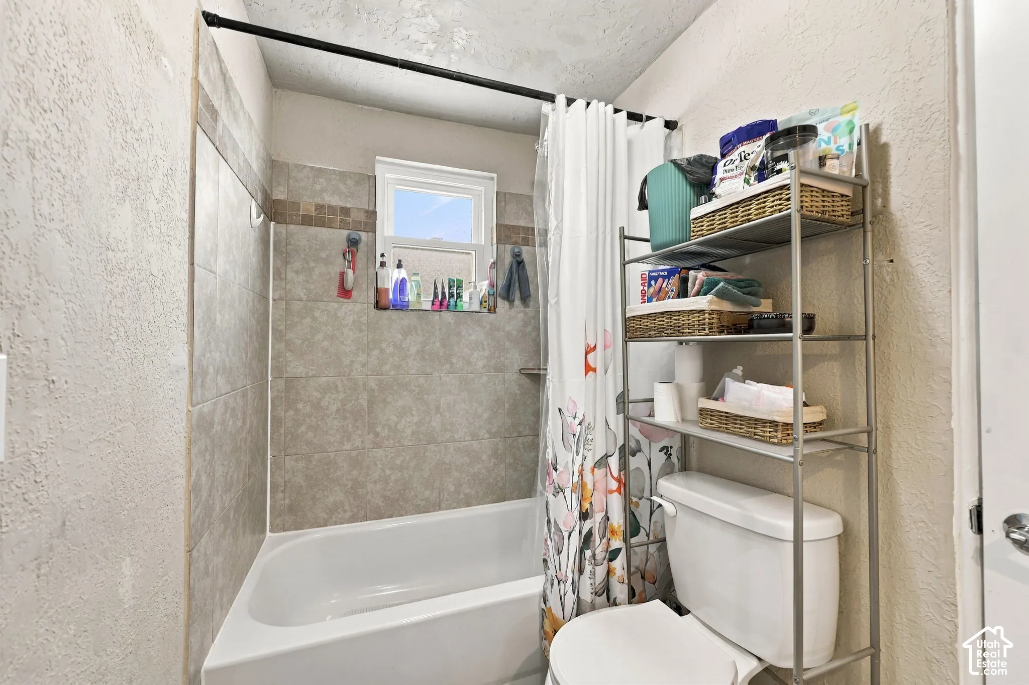 Bathtub with tiled surround, contrasting mosaic accent tile, and a window for natural light