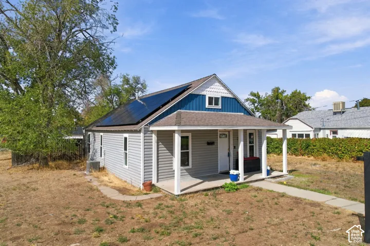 Front porch with white columns, horizontal siding, and prominent roof-mounted solar panels