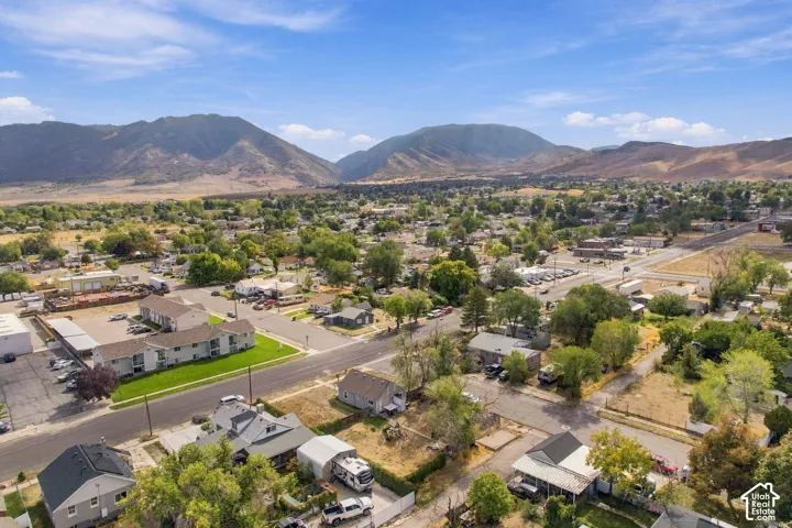 Mountainous terrain in the background, residential and commercial properties, established greenery, paved roads, and clear skies