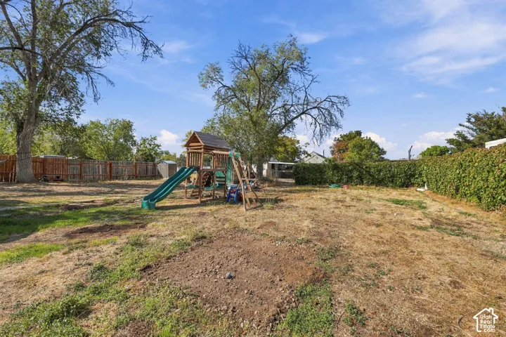 Expansive backyard featuring mature trees, a privacy fence, and a wooden play structure