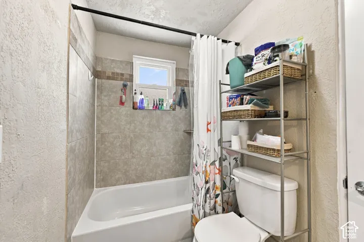 Bathtub with tiled surround, contrasting mosaic accent tile, and a window for natural light