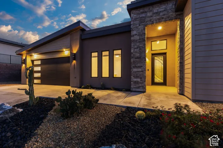 Modern exterior with stacked stone accents, decorative front door, and a two-car garage with frosted glass panels