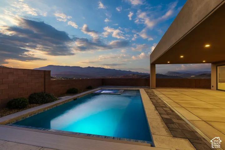 Swimming pool with integrated spa and underwater lighting, a spacious patio area, and a covered outdoor living space