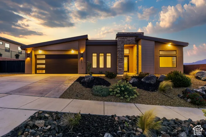 Contemporary stucco exterior with a stone accent facade, featuring a modern garage door with frosted glass panels, and an angled roofline