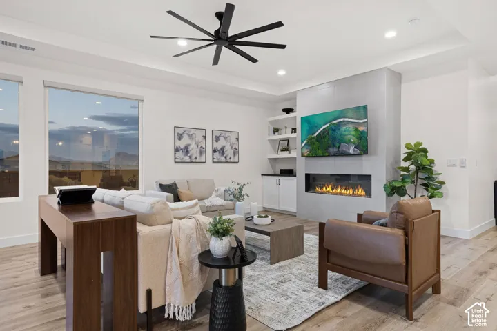 Contemporary living area featuring wood-finish flooring, a linear electric fireplace with a tiled surround, built-in shelving, and recessed lighting
