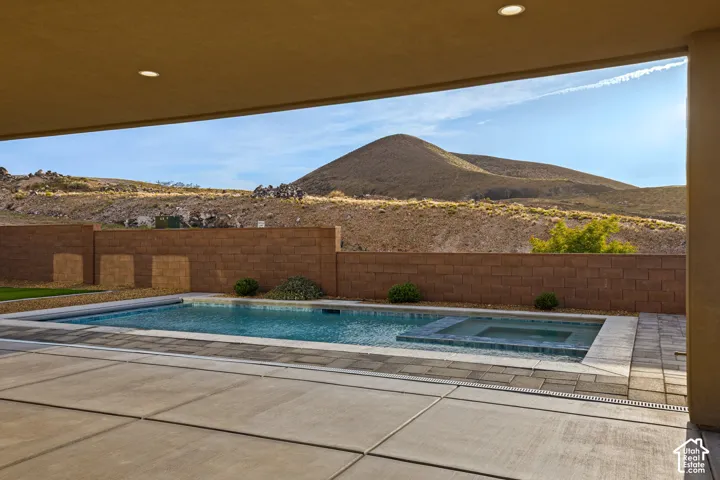 Covered patio with recessed lighting, concrete patio surface, swimming pool, integrated spa, and a block wall perimeter