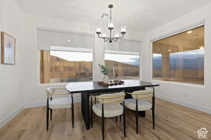 Modern chandelier with a black finish, light wood-finish flooring, and expansive windows
